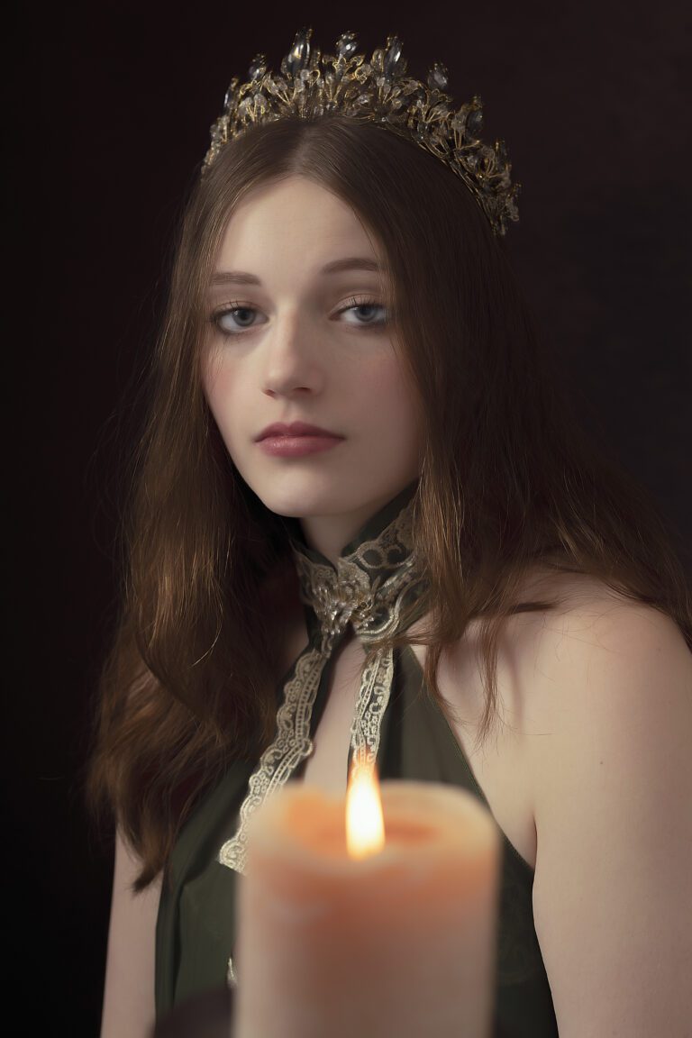 Young woman with long hair gazes thoughtfully, holding a lit candle.