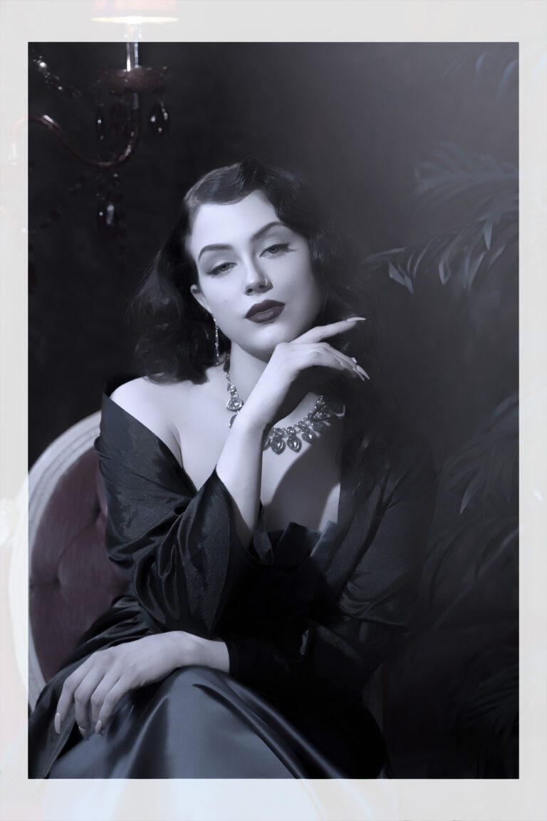 Black and white portrait of a poised woman in vintage attire.