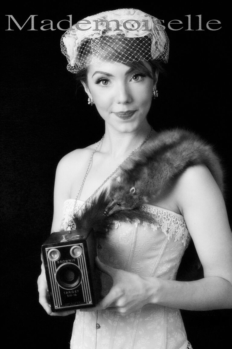 Vintage photograph of a woman holding an old camera, styled in 1920s fashion.