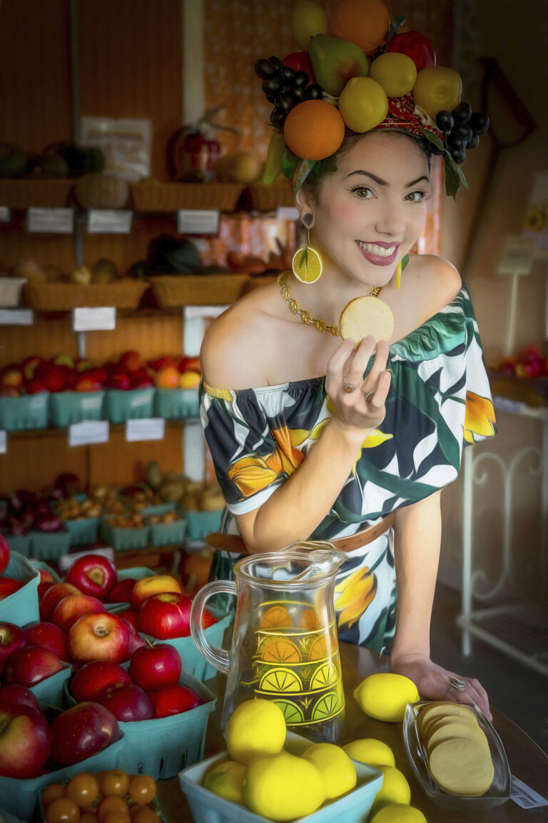 Smiling woman holding a lemon slice in a colorful market setting.