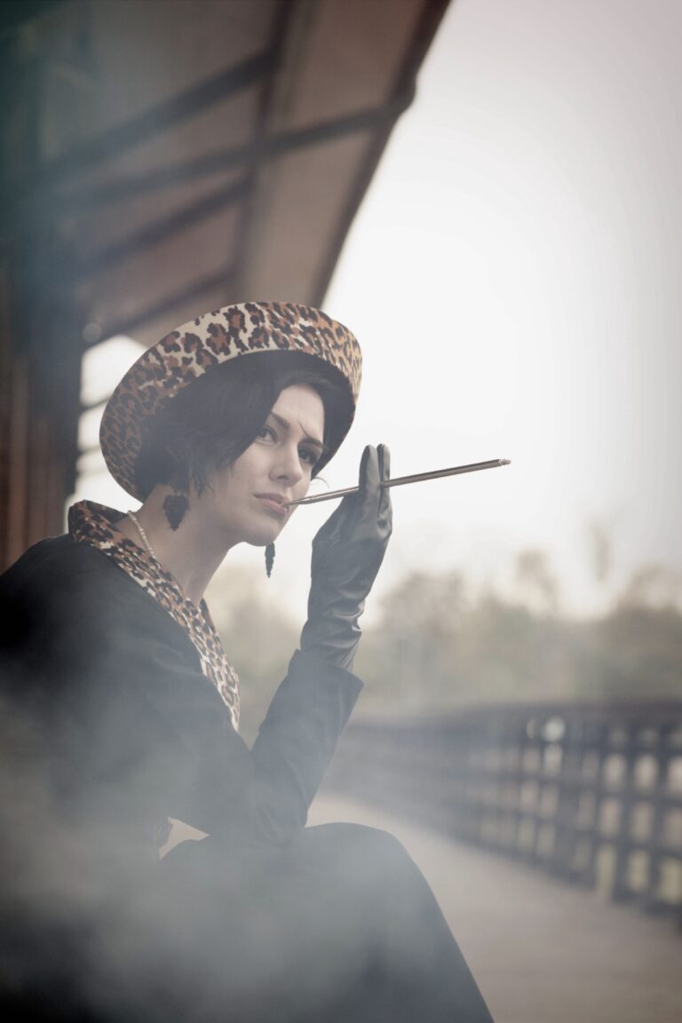 Elegant woman in vintage attire smoking with a contemplative gaze.